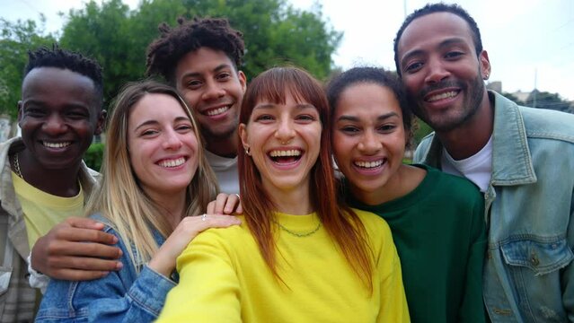 Happy young group of diverse friends having fun doing a video call on mobile phone app during travel vacation. Waving hands. POV. Youth lifestyle and friendship concept
