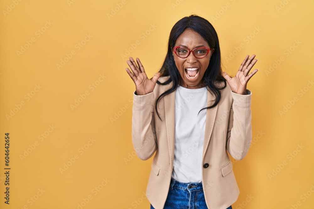 Wall mural African young woman wearing glasses celebrating crazy and amazed for success with arms raised and open eyes screaming excited. winner concept