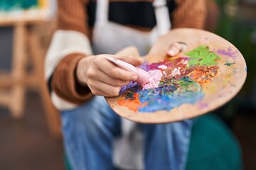 Young woman artist mixing color on palette at art studio
