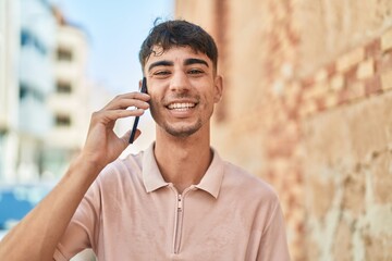Young hispanic man smiling confident talking on the smartphone at street