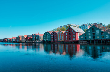 Fototapeta na wymiar A peaceful spring day in Trondheims Bakklandet district, Norway. Blue sky reflects off the water and white buildings of this charming residential area.