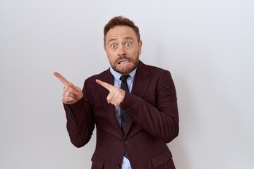 Middle age business man with beard wearing suit and tie pointing aside worried and nervous with both hands, concerned and surprised expression