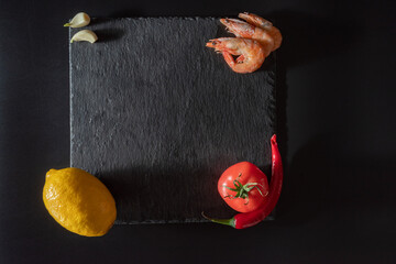 Square stone tray. Products on a slate tray. Red products on a black background. Product contrast. Top view.