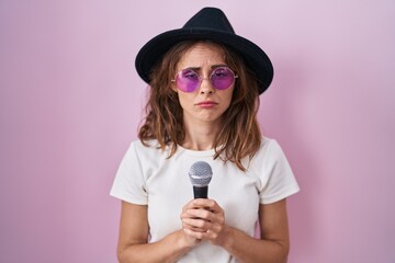 Beautiful brunette woman singing song using microphone depressed and worry for distress, crying...