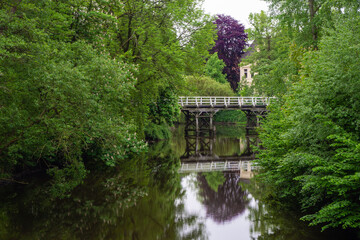 Brücke über Spiegelndem ruhigem Fluss umgeben von Bäumen in vollem Grün