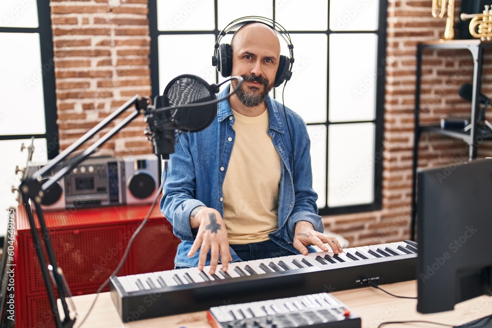 Canvas Prints Young bald man musician smiling confident playing piano at music studio