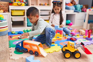 Adorable boy and girl playing with construction blocks and car toy at kindergarten