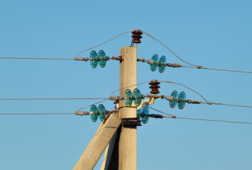 Power line on a concrete pole close-up against a clear blue sky on a sunny day