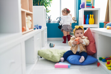 Fototapeta premium Adorable girls sitting on floor playing at kindergarten