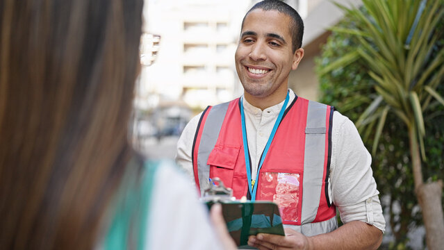 Young hispanic man volunteer speaking with person at street