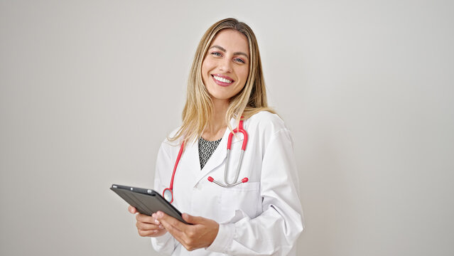 Young blonde woman doctor smiling confident using touchpad over isolated white background