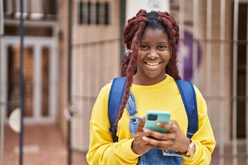 Fototapeta na wymiar African american woman student smiling confident using smartphone at university