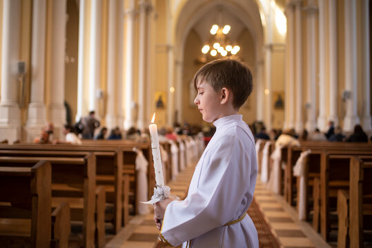boy before first Eucharist in a catholic church. child in white clothes with a candle in the church	