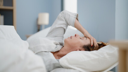 Middle age hispanic woman worried lying on bed at bedroom