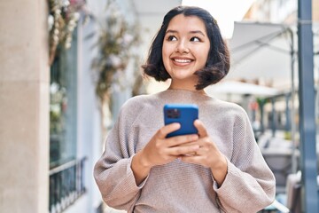 Young woman smiling confident using smartphone at street