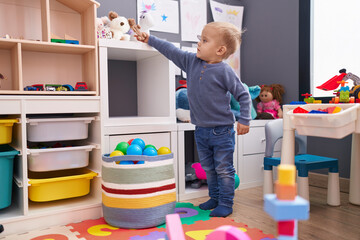 Adorable caucasian boy standing with relaxed expression playing at kindergarten