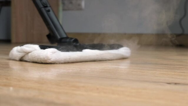 the process of cleaning and mopping the floor with a steam mop, close-up. Environmentally friendly cleaning without the use of detergents. Black mop, white rag.