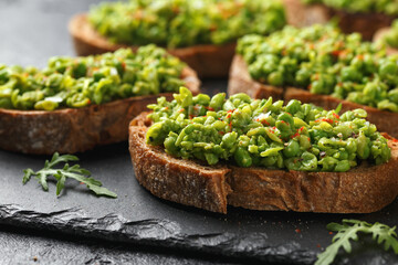 Mashed peas sourdough bread toast with sea salt flakes and chilli served on black slate