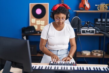 Fototapeta na wymiar African american woman musician playing piano at music studio
