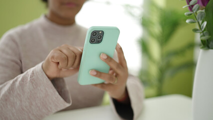 Young african american woman using smartphone sitting on table at home
