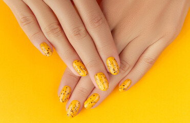 Manicured womans hands with trendy nail design on orange background