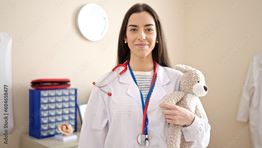 Canvas Prints Young beautiful hispanic woman doctor smiling confident holding teddy bear at clinic