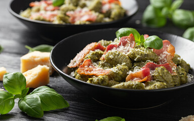 Italian potato gnocchi with green pesto sauce, bacon and parmesan cheese. Healthy food