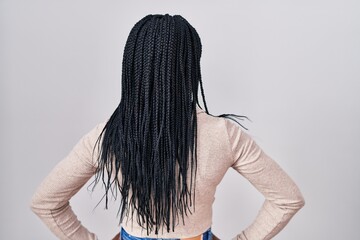 African woman with braids standing over white background standing backwards looking away with arms...