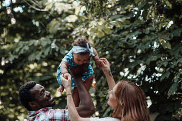 Portrait of candid friendly happy interracial family hold swarthy baby in your arms at camper park