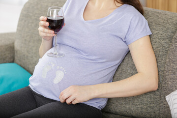 cropped image of pregnant woman holding glass of wine