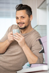 man having coffee in kitchen smiling at camera