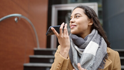 Young beautiful hispanic woman sending voice message with smartphone at street