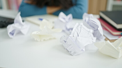 Young beautiful hispanic woman student stressed around crumpled paper at university classroom