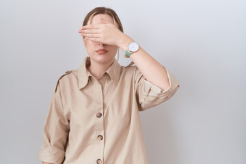 Young caucasian woman wearing casual shirt covering eyes with hand, looking serious and sad....