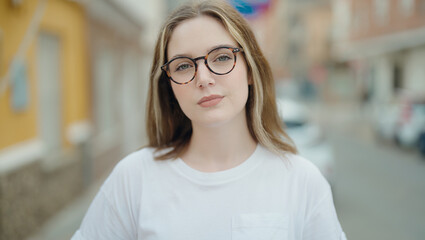 Young caucasian woman wearing glasses standing with serious expression at street