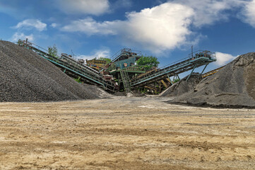 Crushing machinery, cone type rock crusher, conveying crushed granite gravel stone in a quarry open...