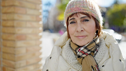 Mature hispanic woman standing with serious expression at street