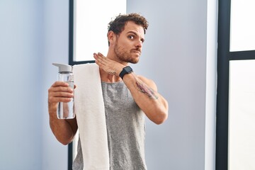 Young hispanic man wearing sportswear drinking water cutting throat with hand as knife, threaten...
