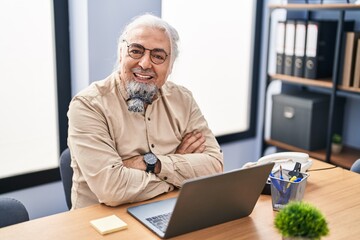 Middle age grey-haired man business worker smiling confident sitting with arms crossed gesture at office