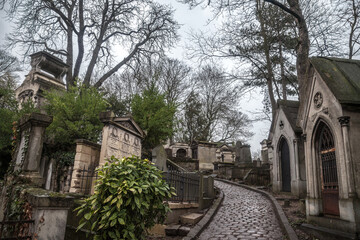 Fototapeta na wymiar PARIS, FRANCE - DECEMBER 22, 2017: Graves from the 19th century in Pere Lachaise Cemetery in Paris, France, during a cold cloudy winter afternoon. Pere Lachaise Cemetery is the largest cemetery in Par