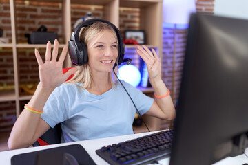 Young caucasian woman playing video games wearing headphones showing and pointing up with fingers number nine while smiling confident and happy.