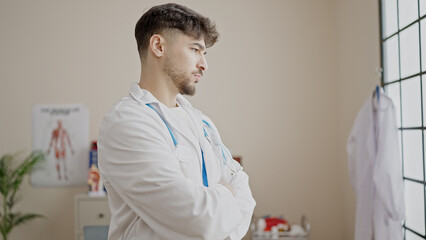 Young arab man doctor standing with arms crossed gesture and relaxed expression at clinic