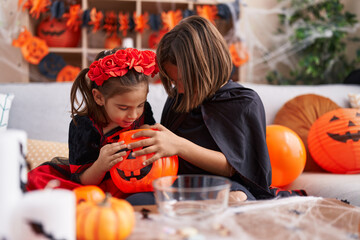 Adorable boy and girl having halloween party looking pumpkin basket at home