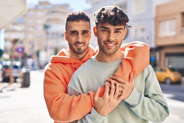 Two man couple hugging each other standing at street