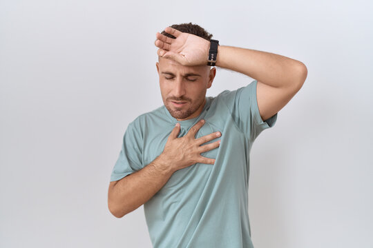 Hispanic man with beard standing over white background touching forehead for illness and fever, flu and cold, virus sick