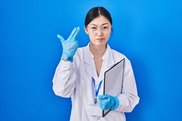 Chinese young woman working at scientist laboratory shooting and killing oneself pointing hand and fingers to head like gun, suicide gesture.