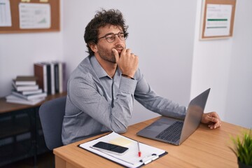 Naklejka premium Young hispanic man business worker using laptop with doubt expression at office