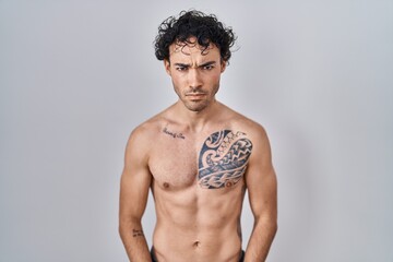 Fototapeta premium Hispanic man standing shirtless skeptic and nervous, frowning upset because of problem. negative person.