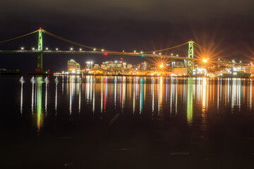 City lights reflecting on water beneath bridge