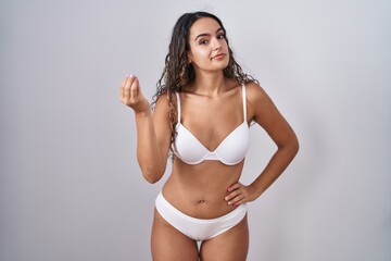 Fototapeta premium Young hispanic woman wearing white lingerie doing italian gesture with hand and fingers confident expression